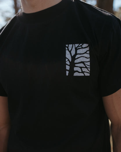Black Bearing Fruit t-shirt with a white tree design on a blurred background