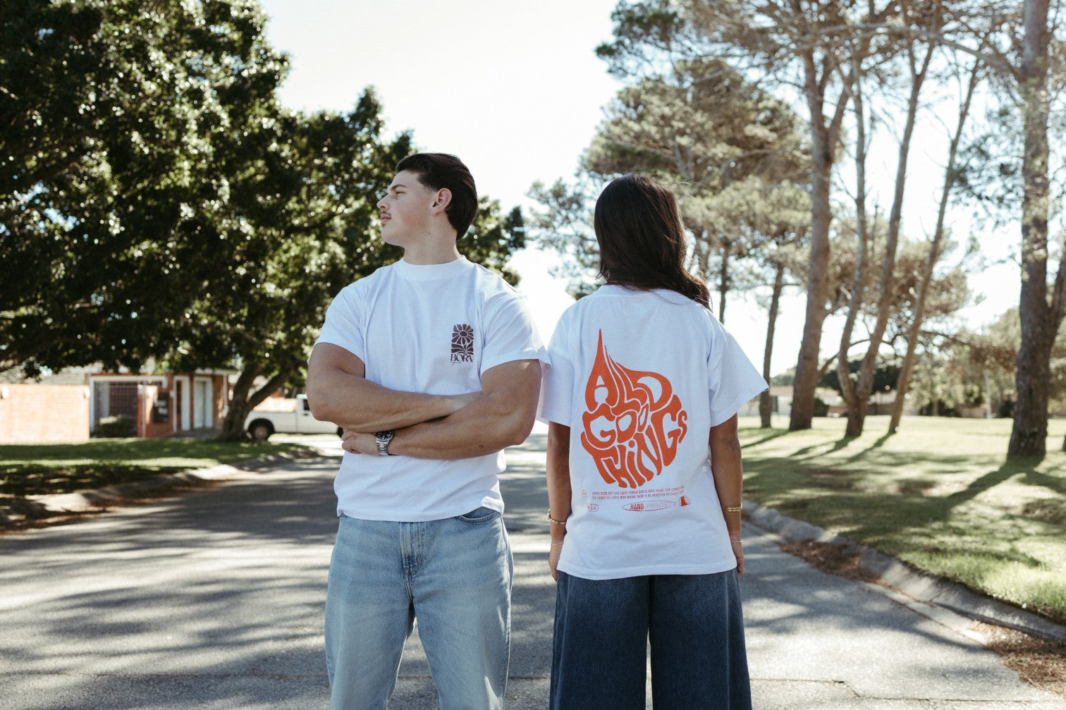 Two people wearing white Christian t-shirts with graphics on a street.
